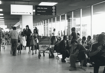 170845 Interieur van één van de vertrekhallen van de luchthaven Schiphol, met wachtende luchtreizigers en linksboven ...